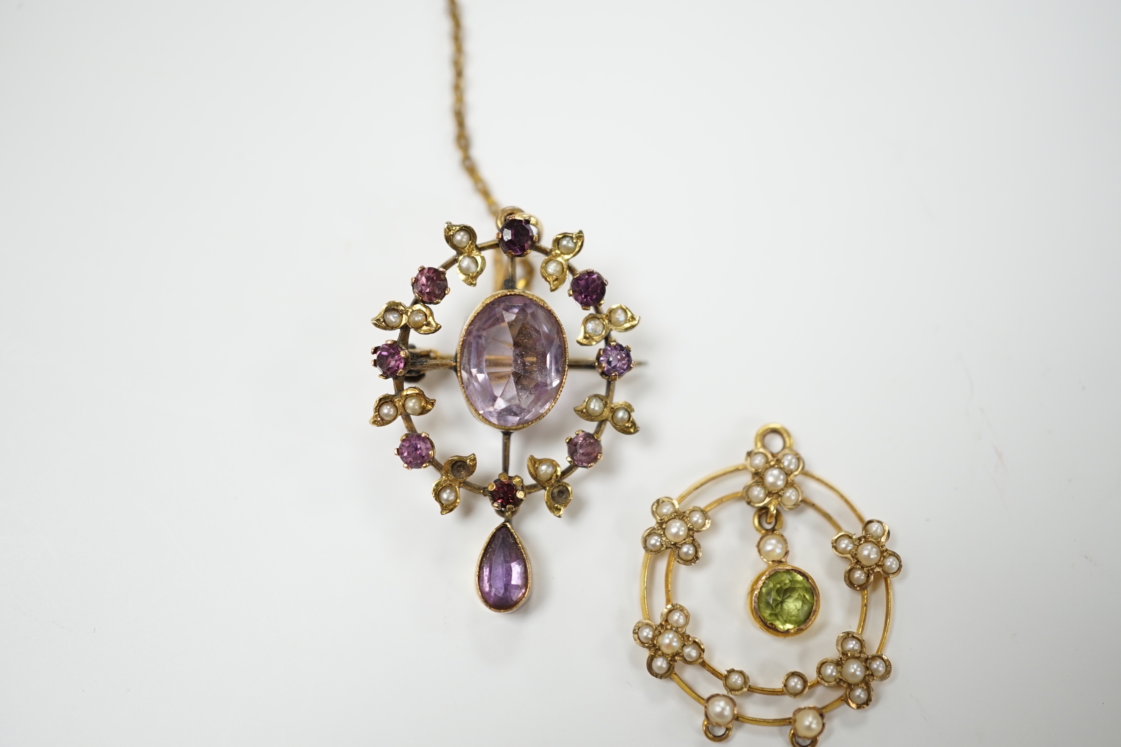 An early 20th century 9ct, peridot and seed pearl set drop pendant, 25mm and one other yellow metal and gem set pendant.